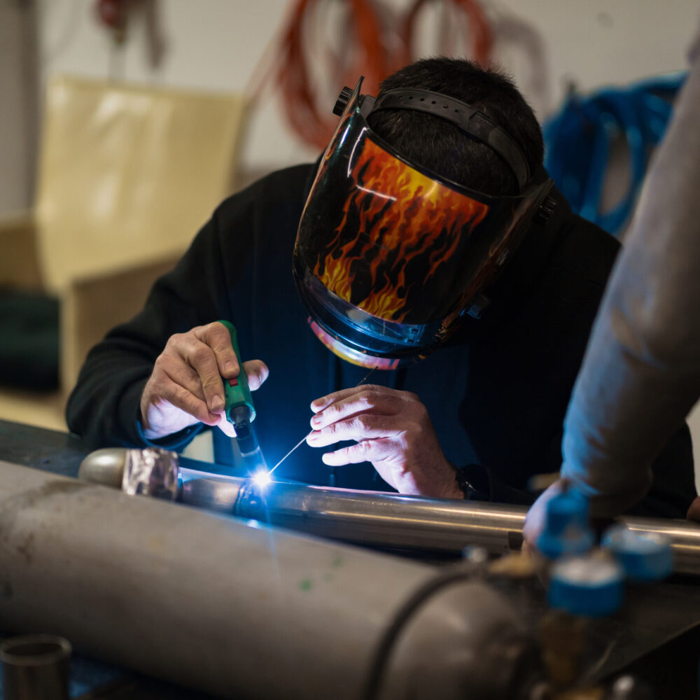Man working with argon welding machine in a garage