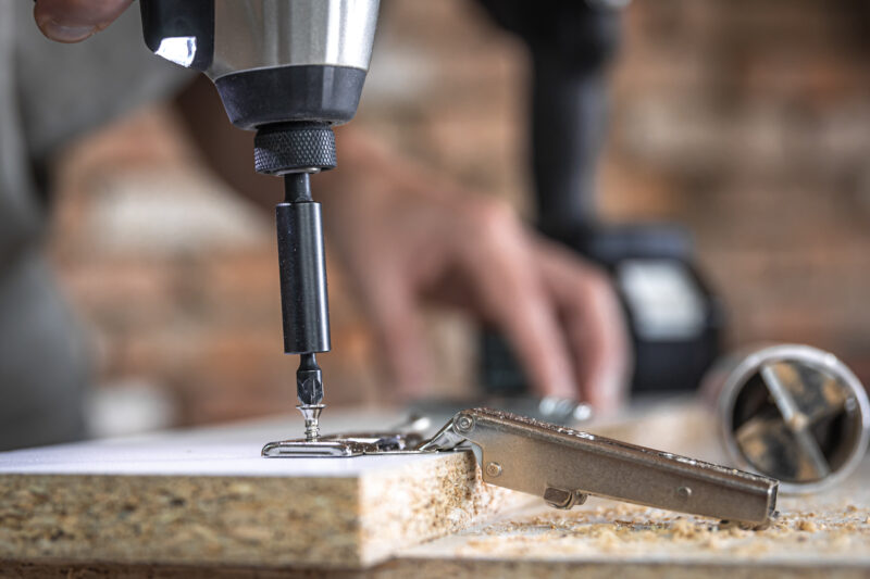 A man is screwing in a screw, a self tapping screw for wood.