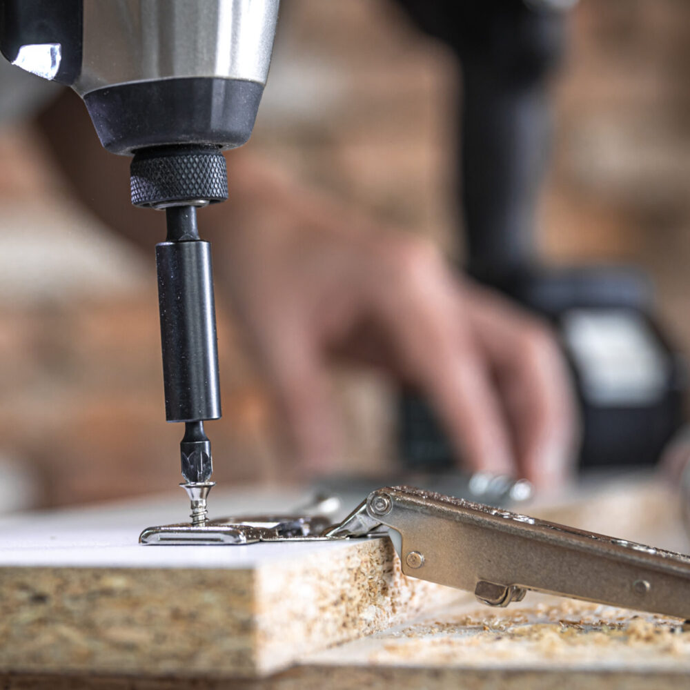 A man is screwing in a screw, a self tapping screw for wood.