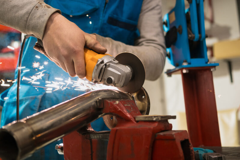 Worker working with a circular grinder on a metal with sparks