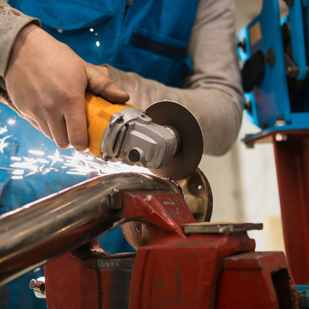 Worker working with a circular grinder on a metal with sparks