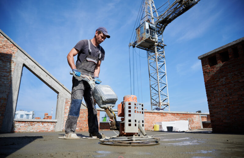 Worker leveling fresh floor with special machine.