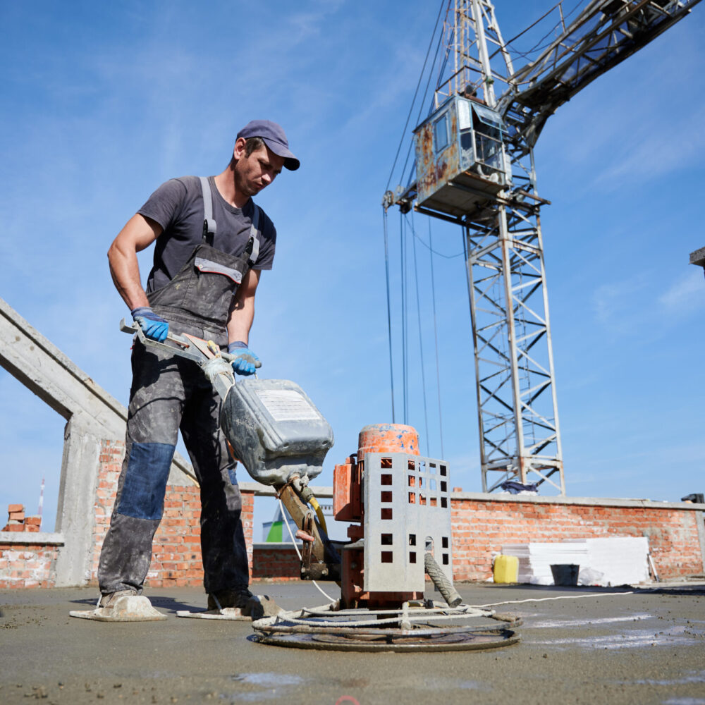 Worker leveling fresh floor with special machine.